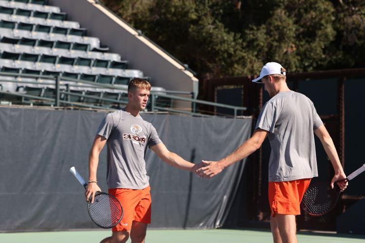 tennis players give each other a high five on the court